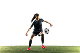 Fototapeta Sport - Young female football or soccer player with long hair in sportwear and boots kicking ball for the goal in jump isolated on white background. Concept of healthy lifestyle, professional sport, hobby.