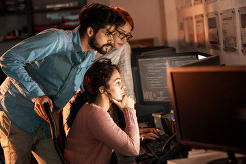 team of programmers working on new project.they working late at night at the office.