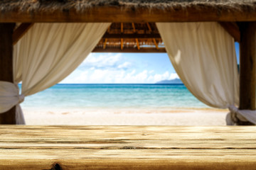  Wooden desk of free space and summer background of beach with sea and wooden window. Summer time 