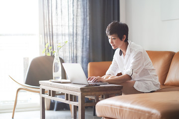 Asian woman working on laptop from home as freelancer