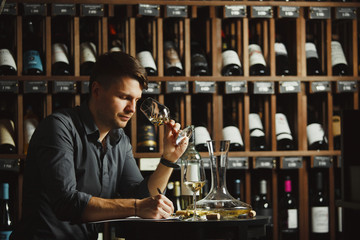 Wall Mural - Sommelier degustating white wine poured in glass