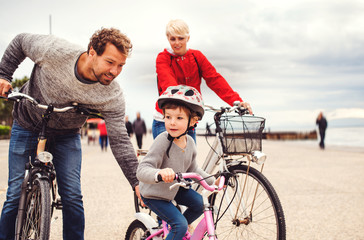 Wall Mural - Young family and small daughter with bicycles outdoors on beach.