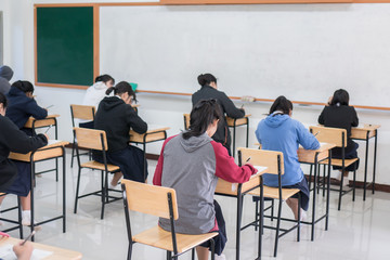 Wall Mural - behind group of asian high school, university student having test exams for taking writing examinati