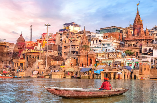 ancient varanasi city architecture at sunset with view of sadhu baba enjoying a boat ride on river g