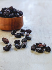 Wall Mural - Dark blue raisins in a wooden bowl on a bright white background. Close-up. Insulated.