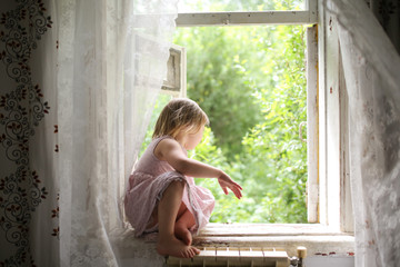 Toddler girl on window in the summer in village