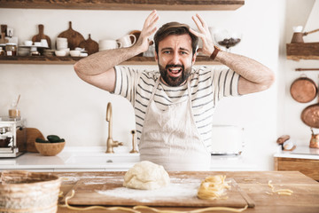 Sticker - Portrait of nervous brunette man making homemade pasta of dough in kitchen at home