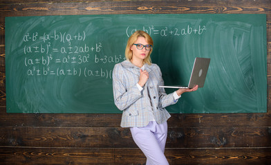 Wall Mural - Teacher blonde woman with modern laptop surfing internet chalkboard background. School innovation. Distance education concept. Lady teacher wear eyeglasses holds laptop surfing internet