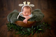 © Oksana - Newborn baby boy in a hat a bamby sleeps in an antique brown wooden bowl