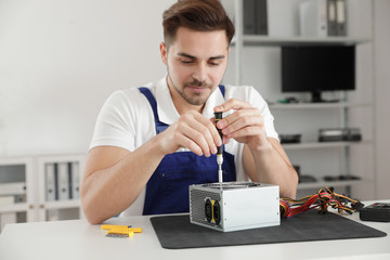 Canvas Print - Male technician repairing power supply unit at table indoors