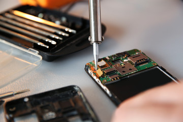 Technician repairing mobile phone at table, closeup