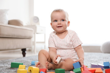 Poster - Cute baby girl playing with building blocks in room