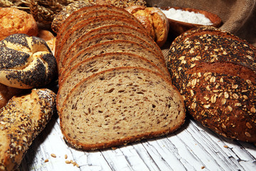 Assortment of baked bread and bread rolls on rustic white bakery table background