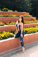 Wall Mural - stylish girl posing near the flowerbeds and looks into the camer