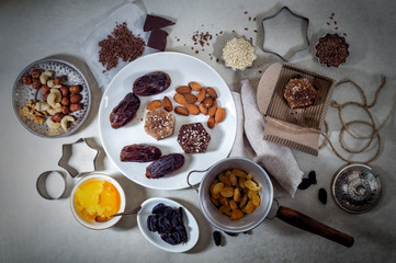 Natural useful sweets from dates, nuts, honey and raisins on a white plate. These ingredients are next on the table