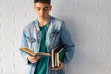 young teenager or fashion student with books supported on the wall