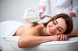 © artiemedvedev - Young pretty smiling woman back laser epilation in beauty salon. Cosmetologist doing depilation treatment with elos device. Beautician hands in gloves holding hair removal cosmetology ipl hardware