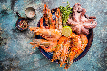 Top view of big plate with grilled shrimps and octopus tentacles decorated with greenery