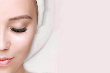 Eyelash extension procedure. Beautiful woman with long eyelashes and perfect glow clean skin. Girl in beauty salon getting facial treatment. Perfect trendy eyebrows.