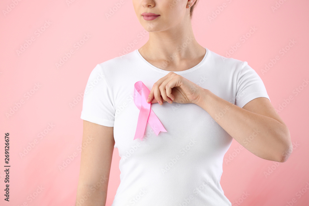 Young woman with pink ribbon on color background. Breast cancer awareness concept