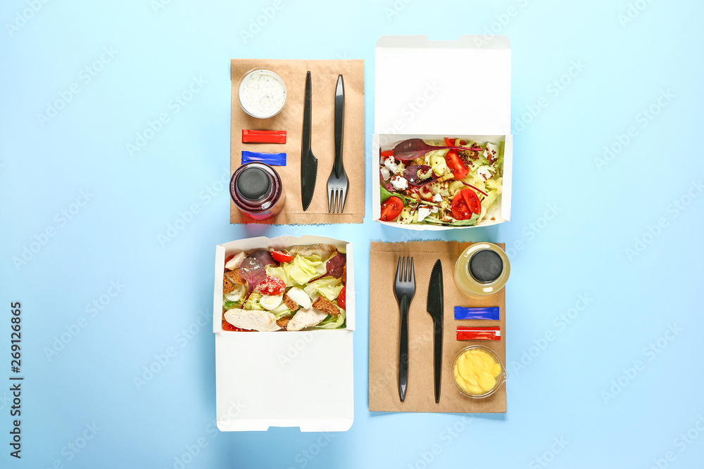 Containers with delicious food and drinks on color background