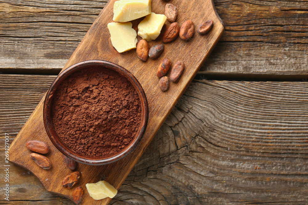 Bowl with cocoa powder on wooden background