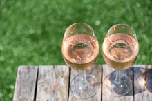 Two Glasses Of Rose Wine On A Wooden Table In Sunlight Top View With Grass In The Background