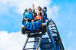 canvas print picture - Young family having fun riding a rollercoaster at a theme park. Screaming, laughing and enjoying a fun summer vacation together.