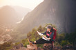 © ittipol - Backpacker woman sitting on top of mountain and looking map with nature background