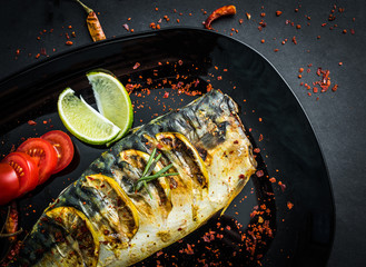 Wall Mural - Grilled mackerel fillets on black plate, fried fish and vegetables