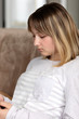 © Светлана Горбань - Girl teenager sitting on the couch in the room, looking into the phone and listening to music on headphones.