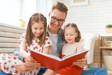 Wall Mural - father reading a book to his daughters