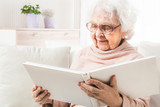 Eldery woman looking photos in white photo album