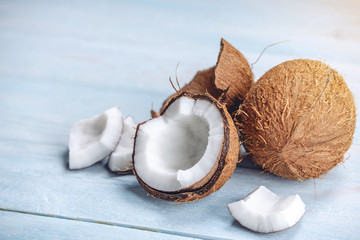 Open coconut with white pulp on blue wooden background. Organic healthy vegan product widely used in cosmetics