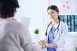 © lenets_tan - Female doctor calming down a patient at a hospital consulting room, holding her hand
