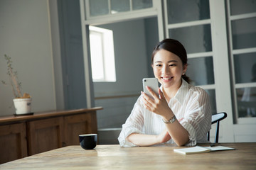 部屋でスマホを見て笑顔の20代女性