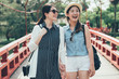 © PR Image Factory - two asian girl friends on walking on beautiful wooden bridge in japanese traditional park. red small arched bridge over stream. young women on walk way crossing pond outdoor on sunny day talk smiling