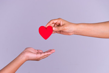 Woman hand gives a red heart to a boy hand for blood donation concept,World blood donor day. Copy space for advertisers.
