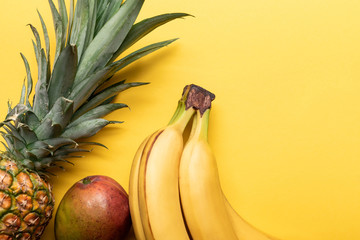 Sticker - top view of whole ripe bananas, pineapple and mango on yellow background