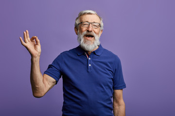 happy positive handsome old man shows Ok sign, no problems, health is ok.everything is ok. close up portrait. isolated blue background. happiness, success concept