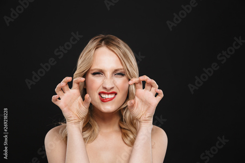 Blonde flirting growling woman with bright makeup red lips posing isolated over black wall background Tableau sur Toile