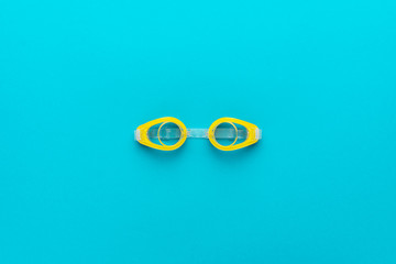 flat lay shot of yellow swimming goggles over turquoise blue background. minimalist photo of swimming goggles with central composition