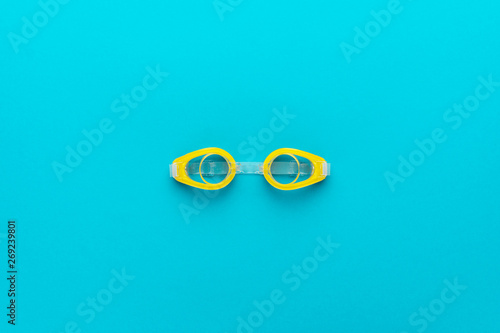 Fotomural flat lay shot of yellow swimming goggles over turquoise blue background