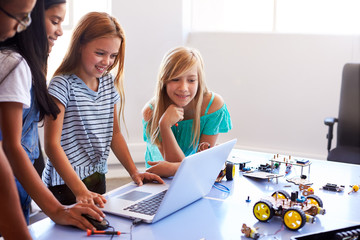 Wall Mural - Three Female Students With Teacher Building Robot Vehicle In After School Computer Coding Class