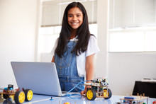 Portrait Of Female Student Building And Programing Robot Vehicle In School Computer Coding Class