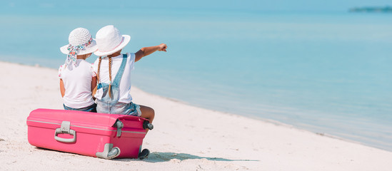 Little girls with big suitcase and map at tropical beach