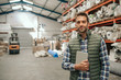 © mavoimages - Smiling worker holding his digital tablet in a large warehouse
