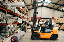 Forklift Driver Carefully Moving Stock Around A Large Warehouse