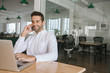 © mavoimages - Smiling businessman talking on a cellphone and using his laptop