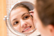 © sosiukin - Beautiful woman with tweezers is plucking eyebrows while looking into the mirror in bathroom. Beauty skincare and wellness morning concept